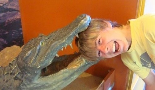 Image of a boy taking picture with an alligator statue
